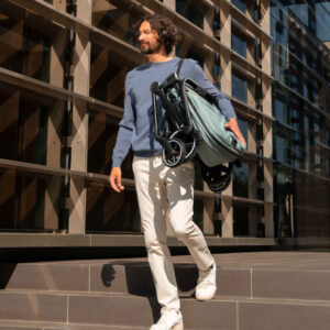 Man carries folded stroller on his shoulder